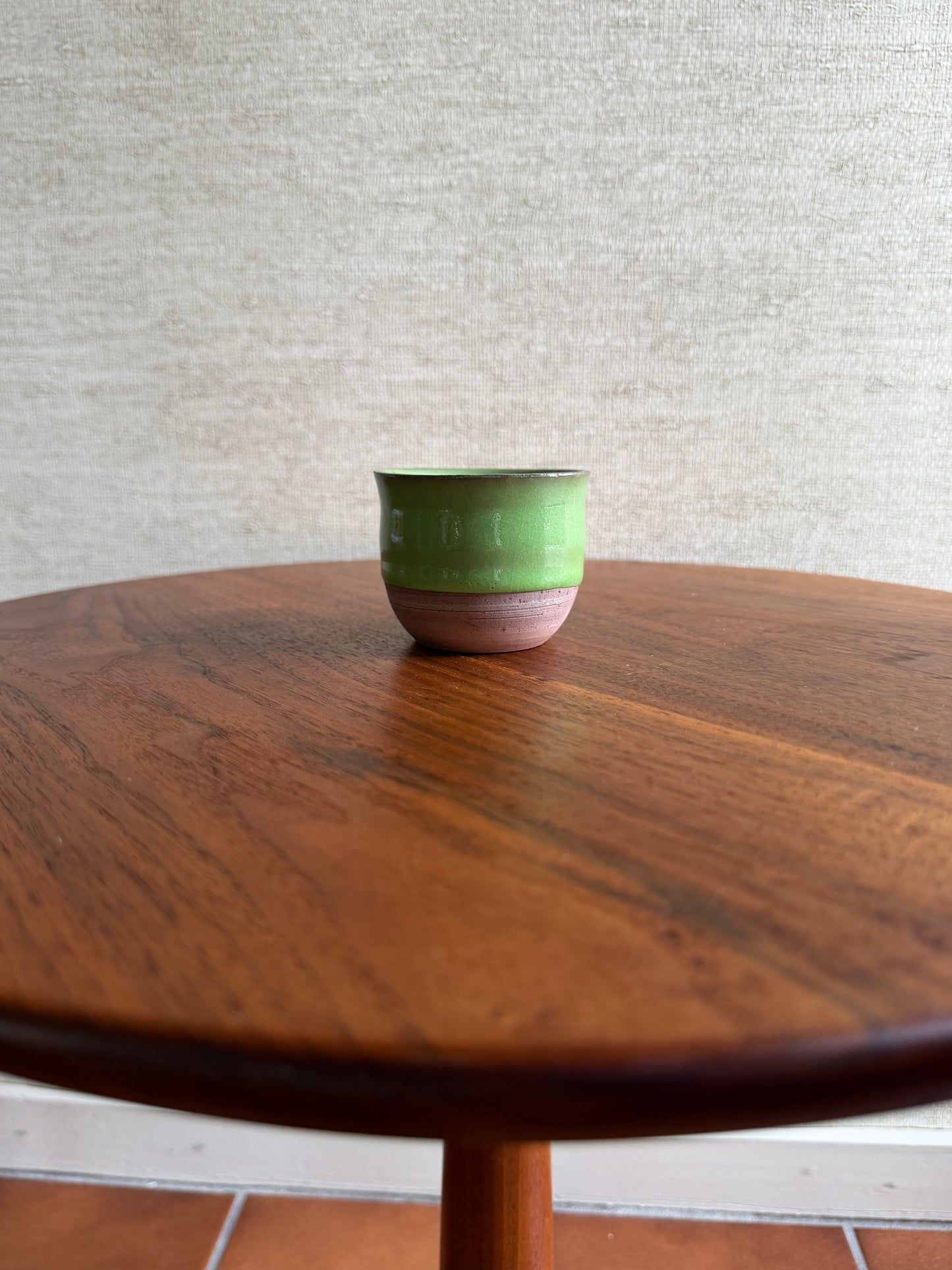 Green ceramic cup on a wooden table with a neutral background