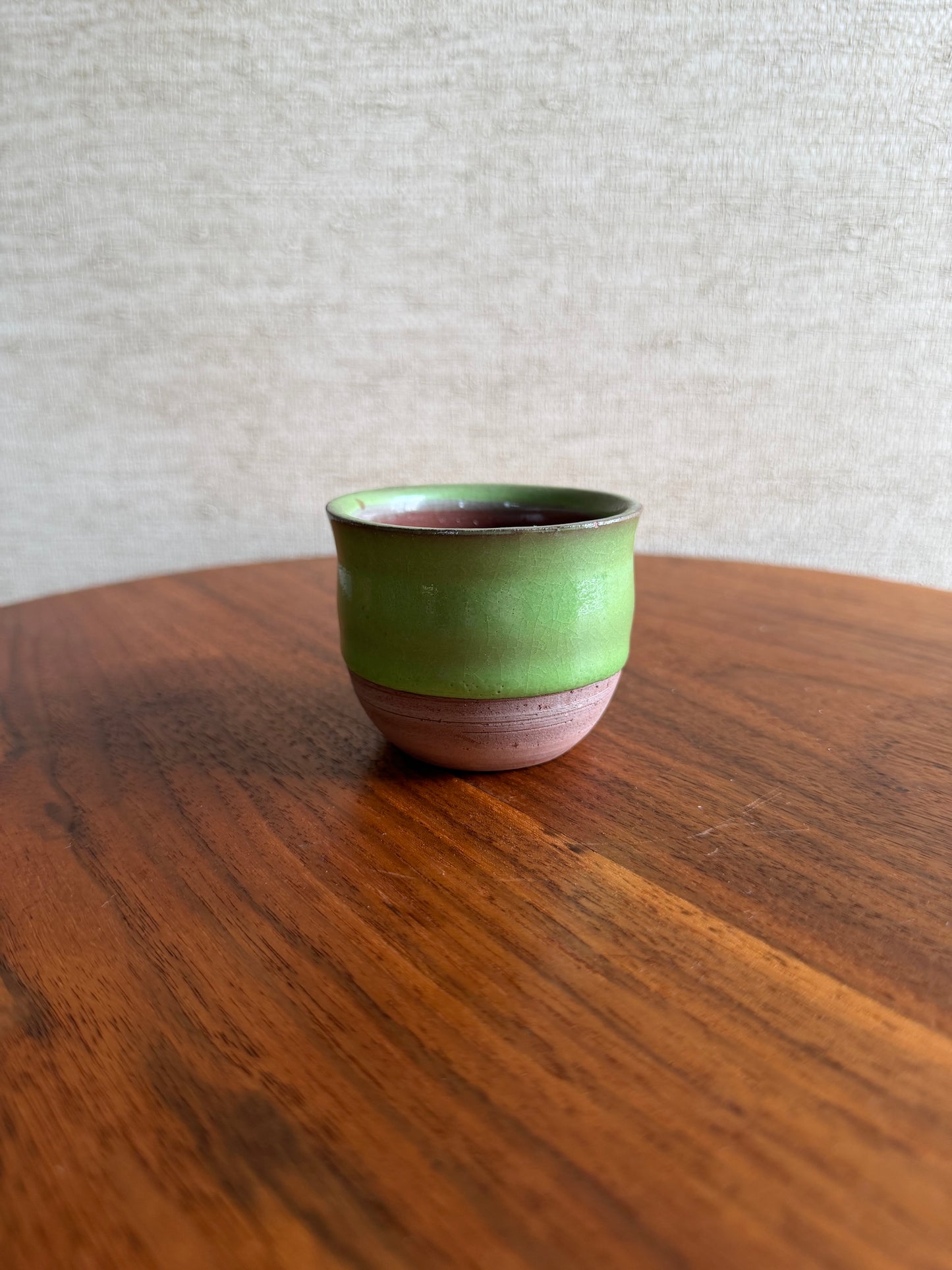 Green and pink cylindrical object on a wooden surface