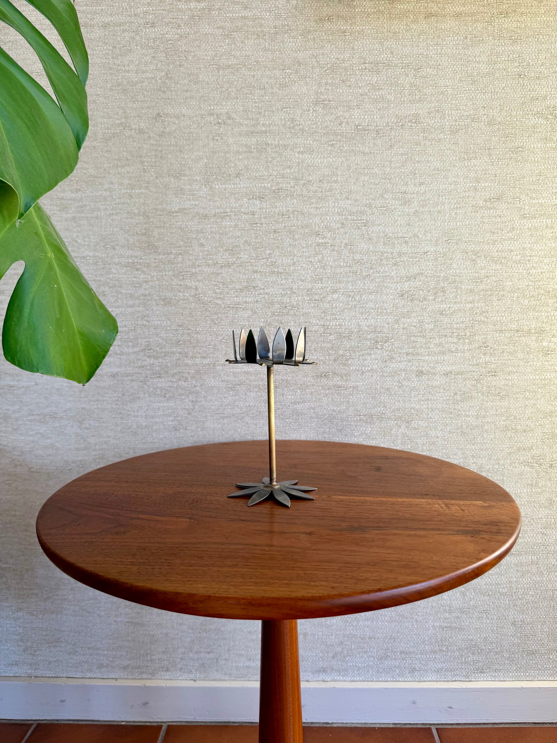 Wooden table with a decorative candle holder against a textured wall.
