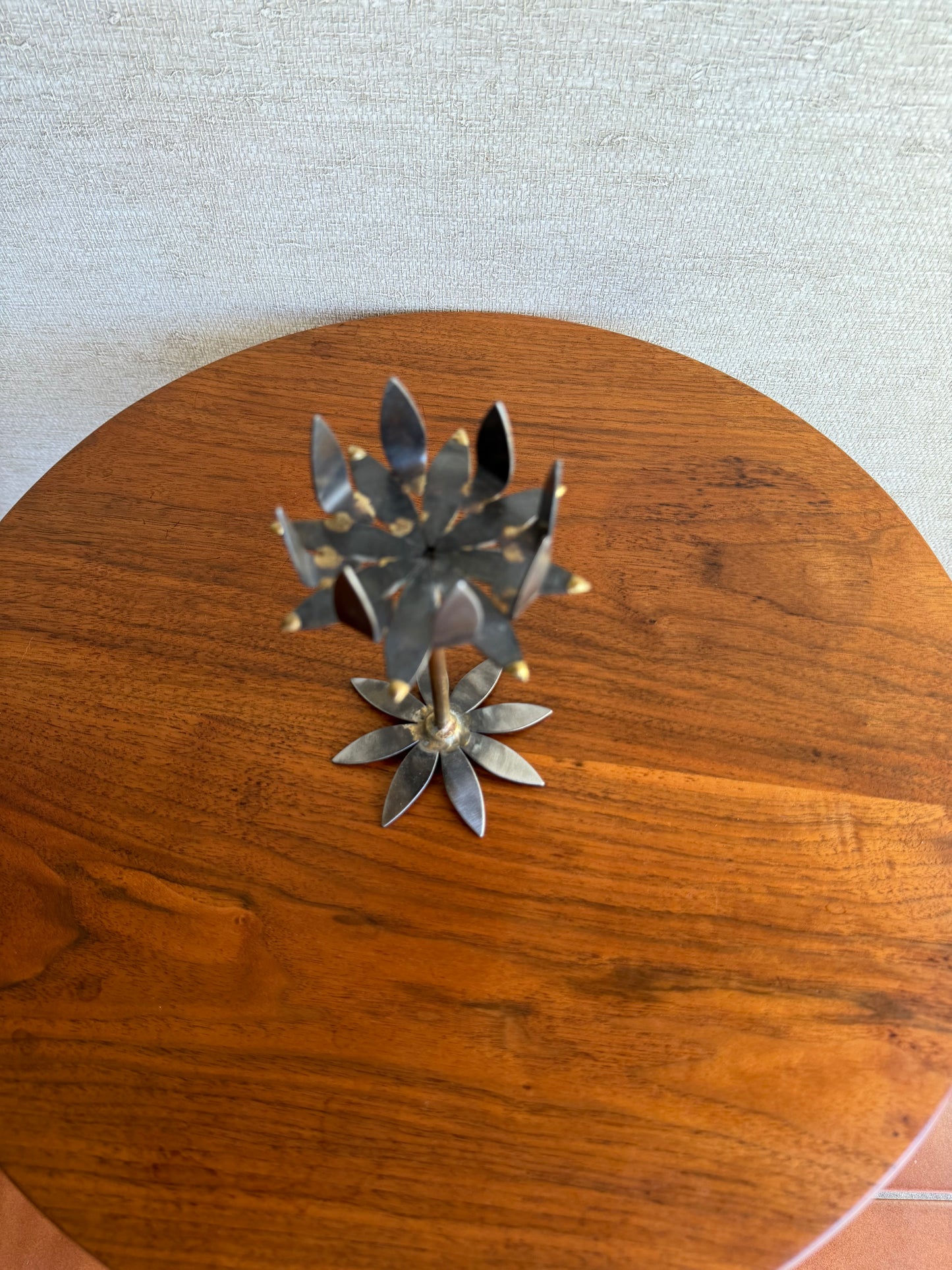 Decorative metal flower candleholder on a wooden circular table against a light background