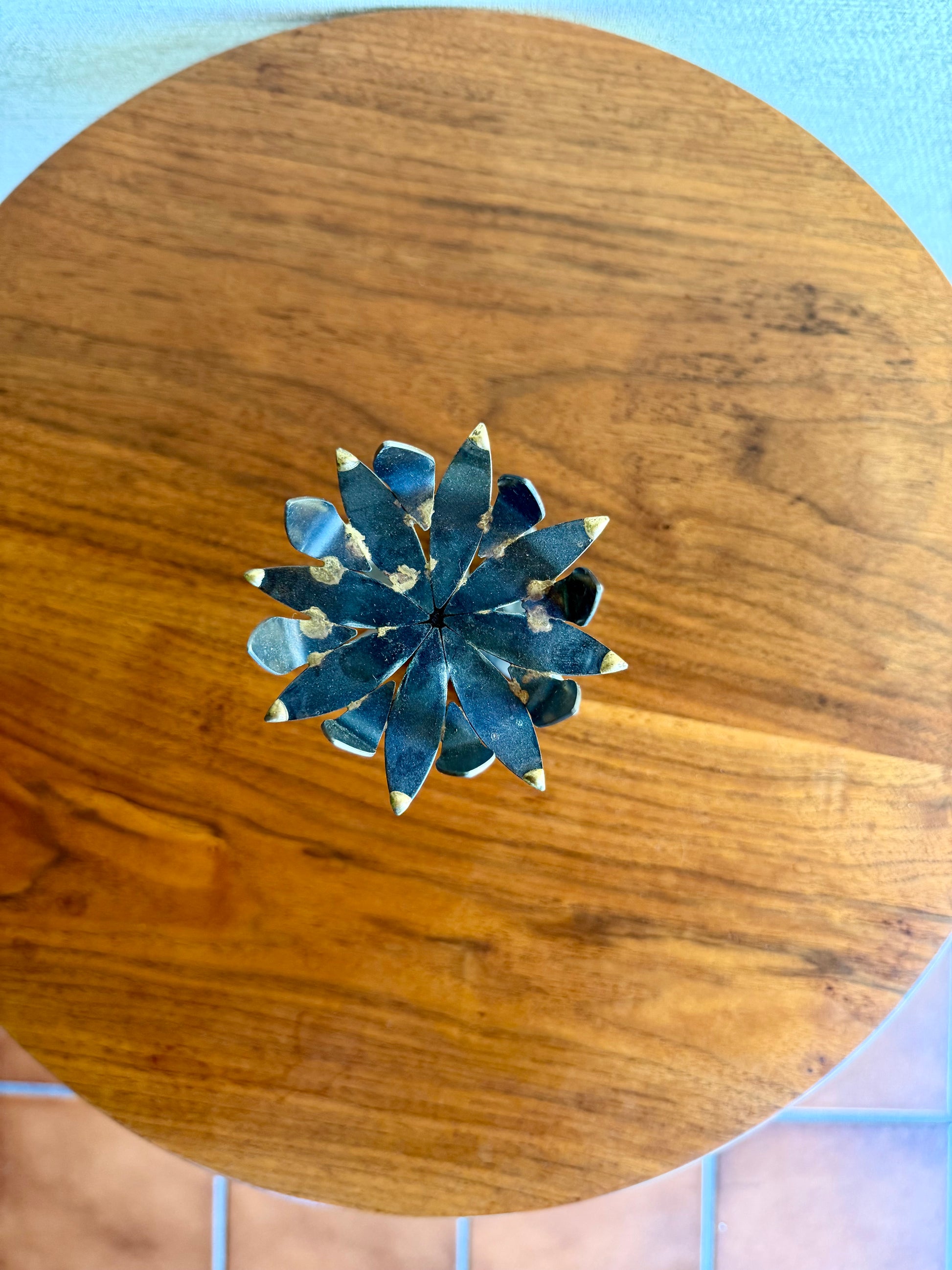 Decorative black and brass metal flower candleholder on a wood table