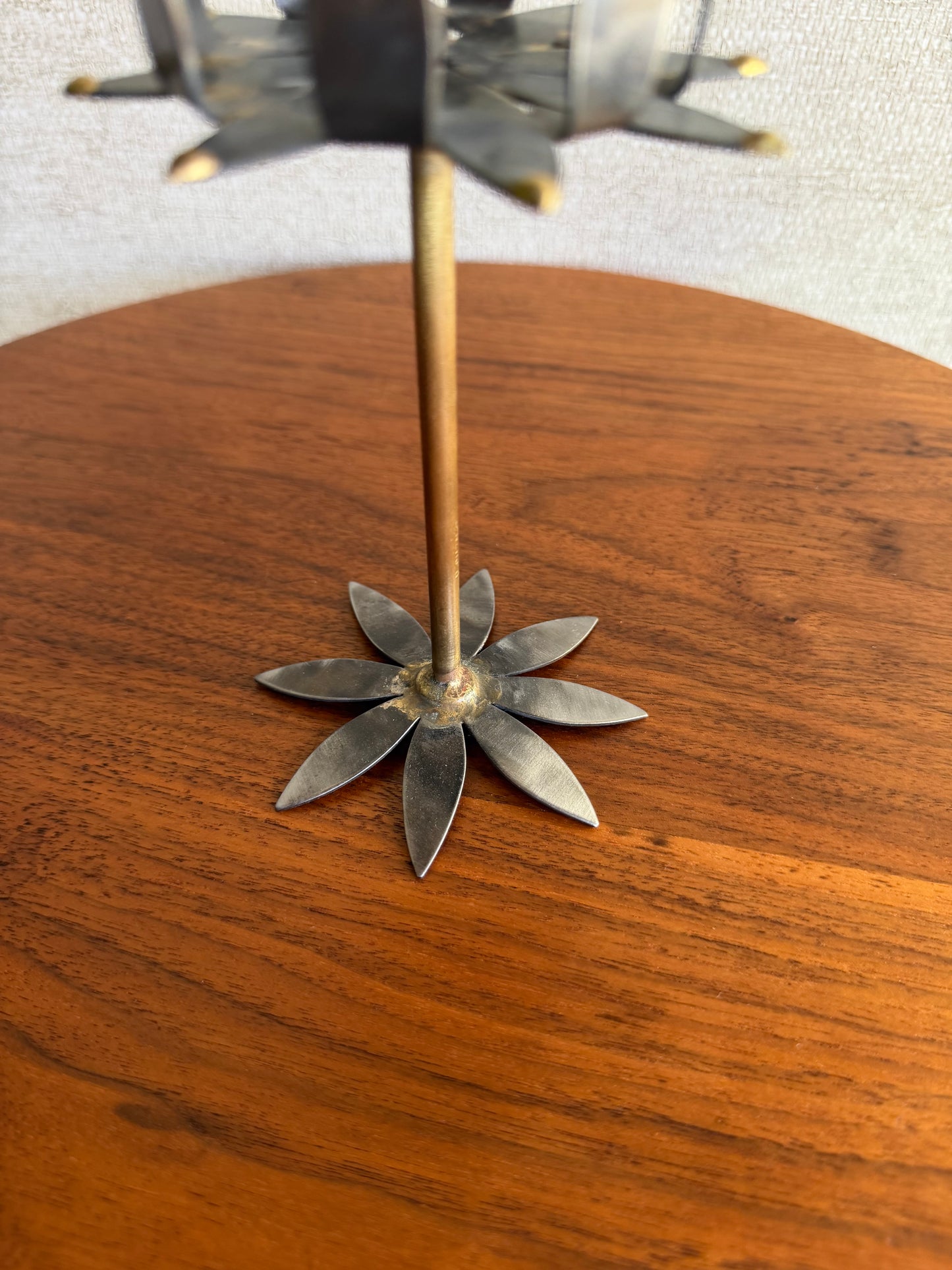 Metal flower-shaped object on a wooden surface with a blurred background