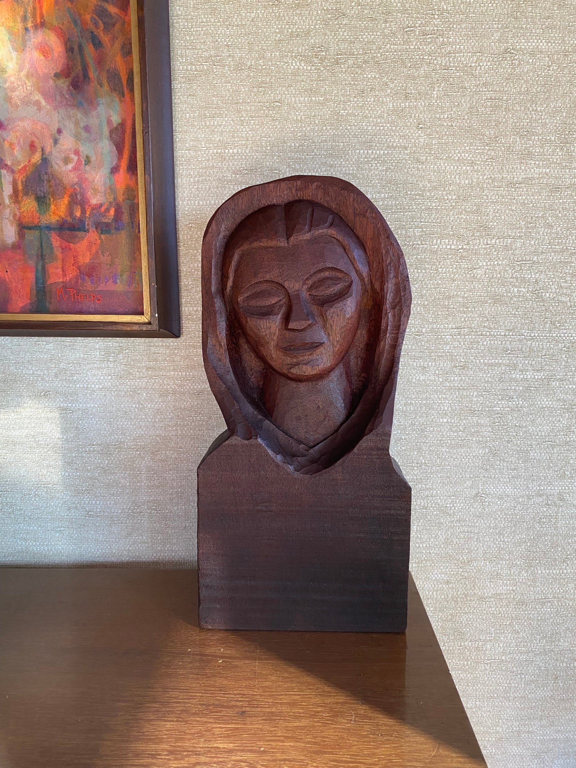 Wooden sculpture of a face on a wall with a painting below