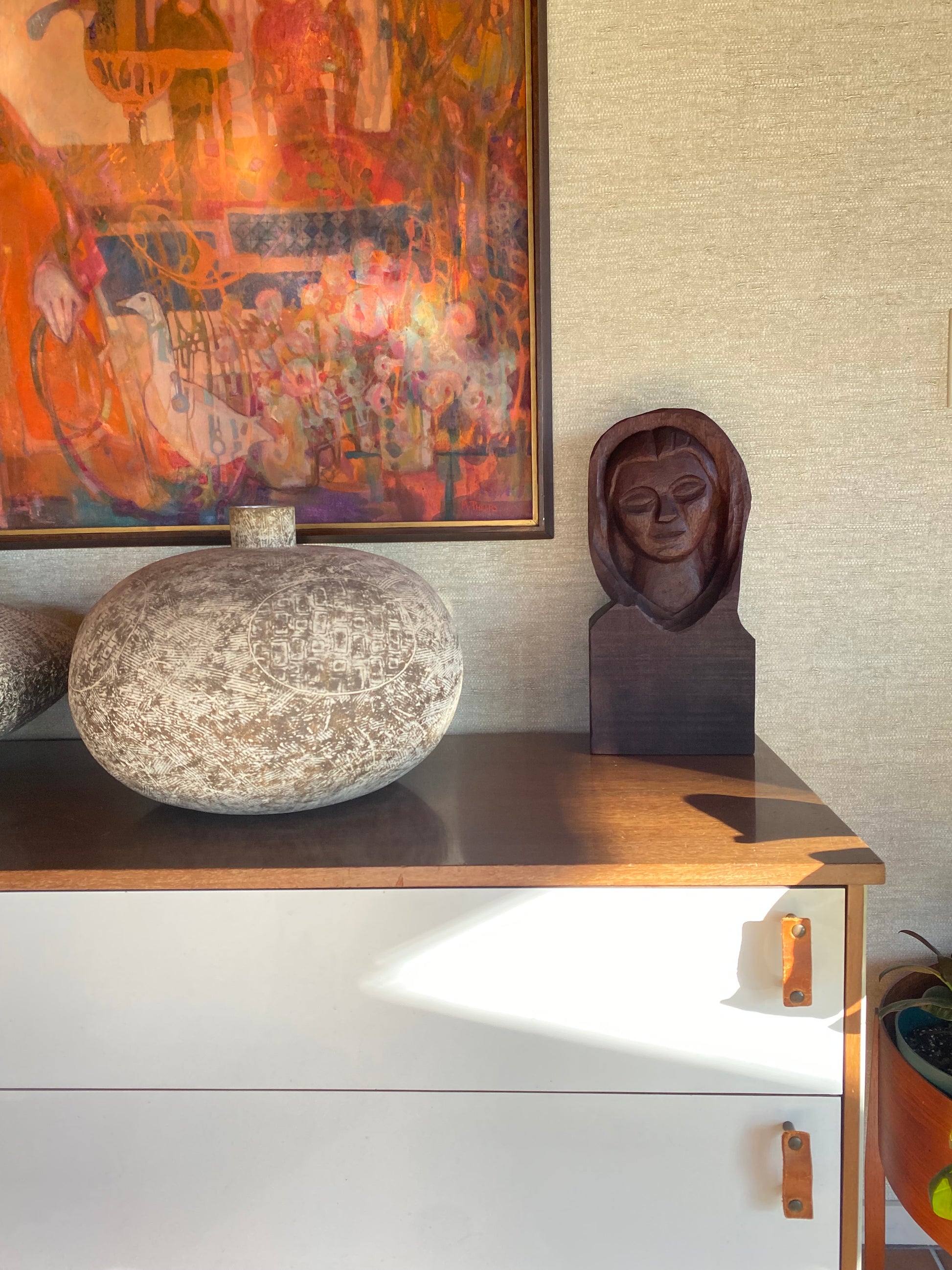 Decorative items including a framed painting, sculpture, and stone on a textured wall.