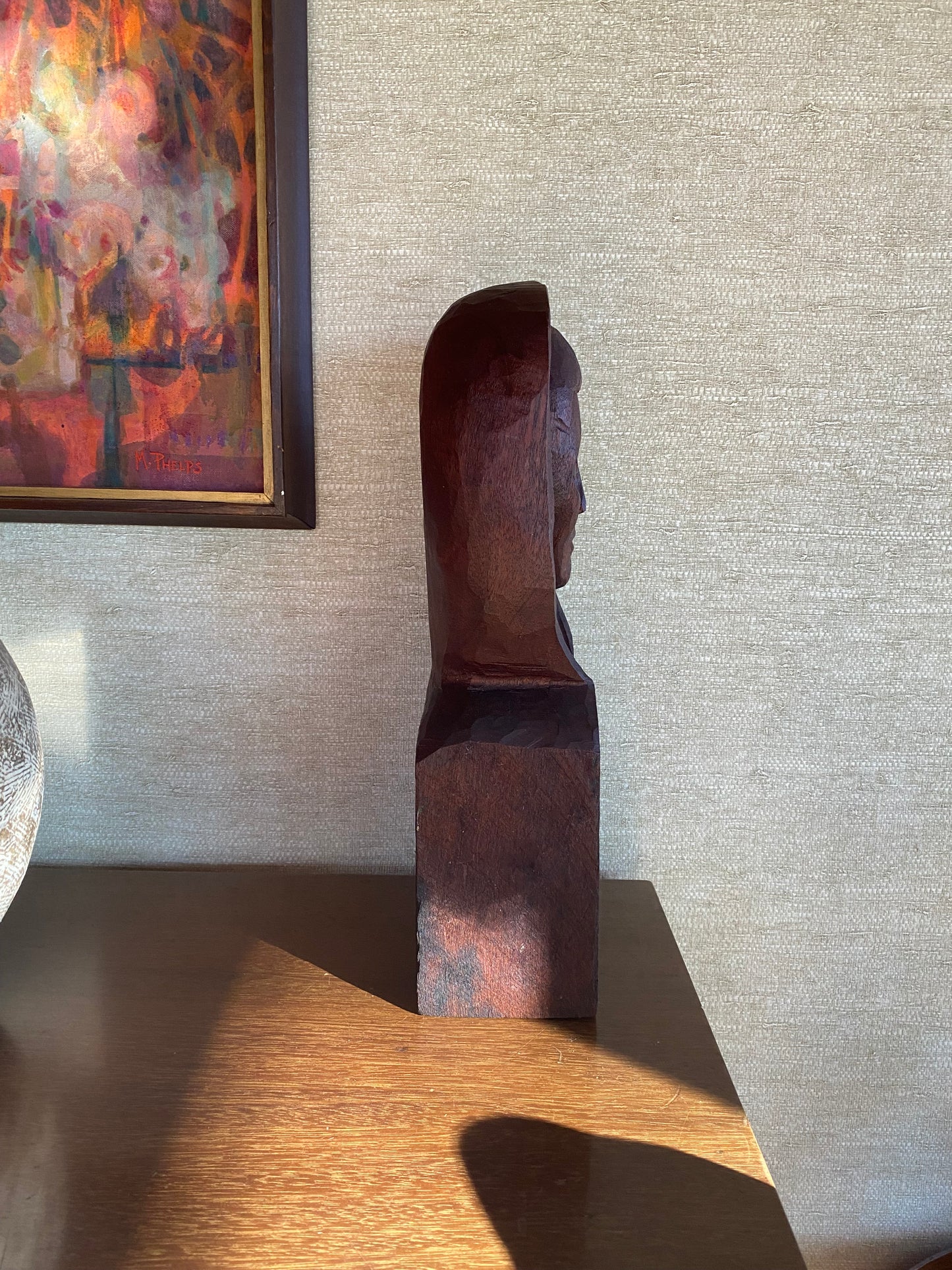 Abstract painting on a textured wall with a wooden sculpture leaning against it.