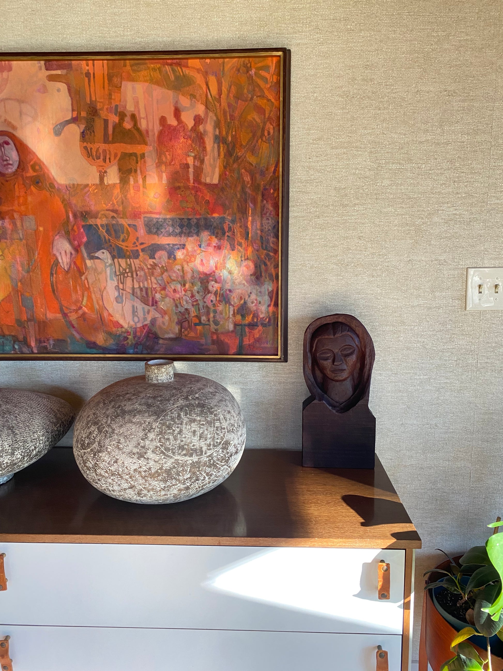 Decorative items including a framed artwork, a stone sculpture, and a wooden mask on a textured wall.