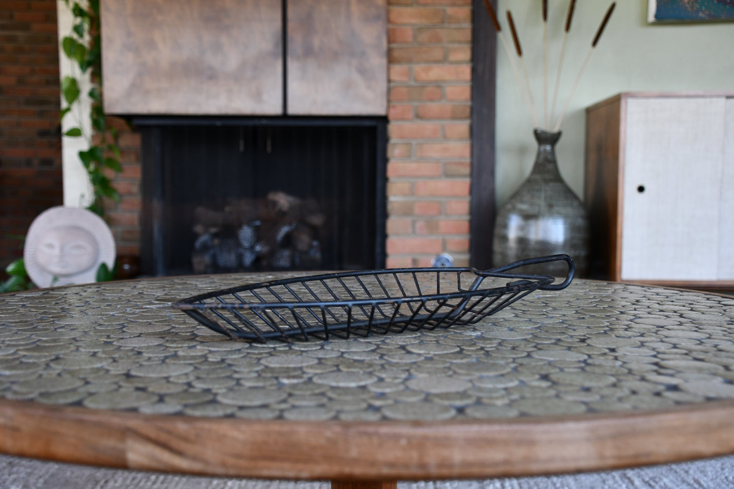 Wire fruit basket on a stone-topped table with a fireplace in the background