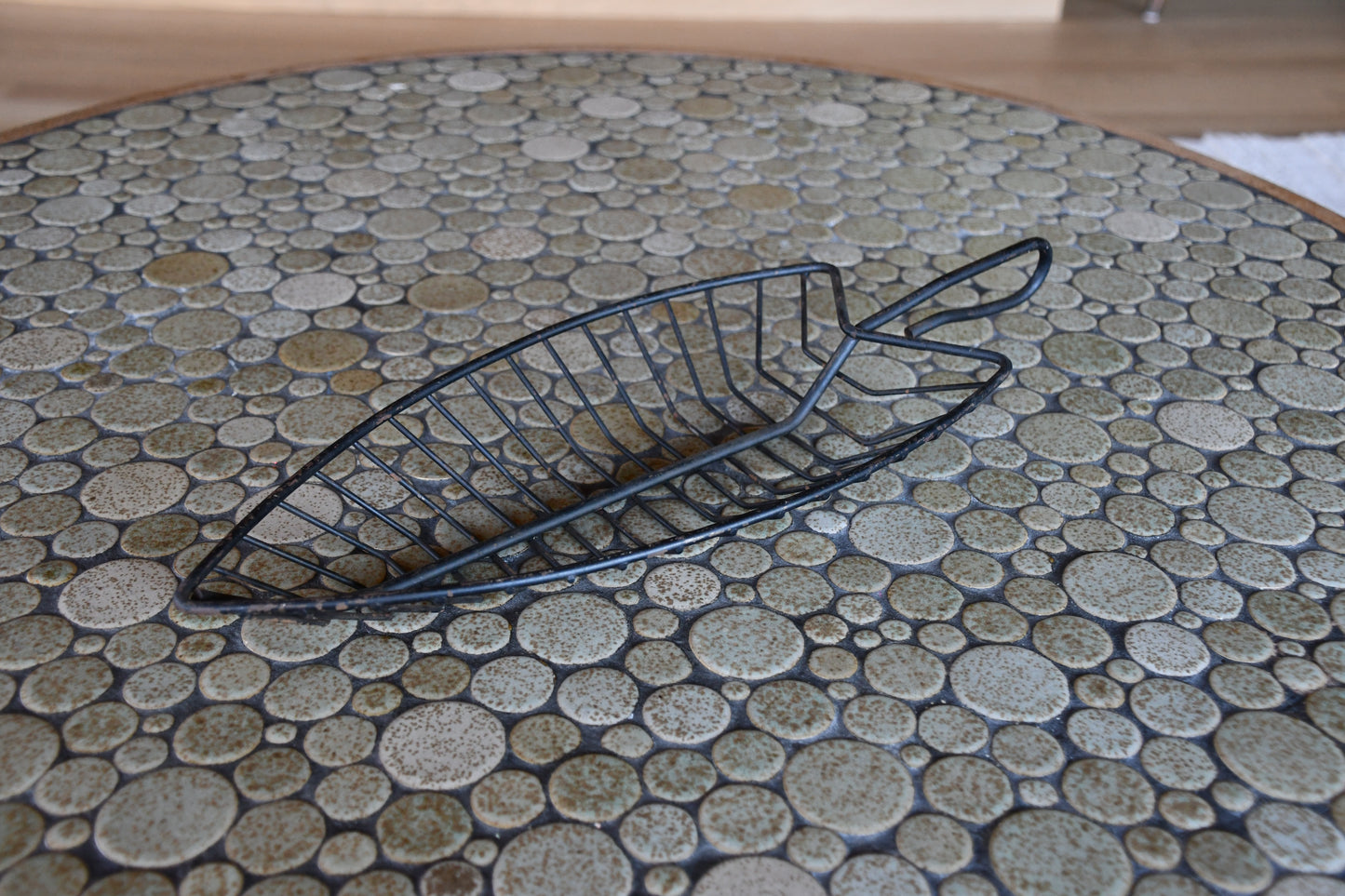 Black wire basket on a round table with a pebble-like surface