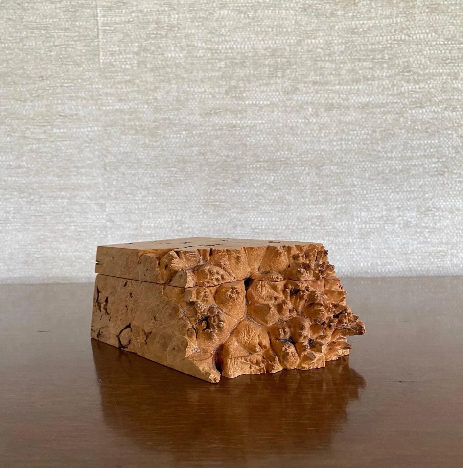 Wooden box with a natural, textured surface on a reflective surface with a neutral background