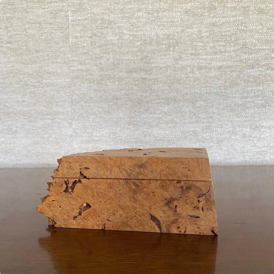 Wooden box with a textured surface on a reflective surface with a light gray background