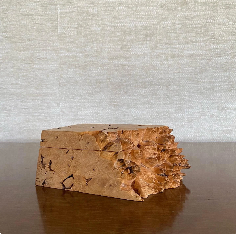 Wooden box with a natural, textured surface on a reflective surface with a neutral background