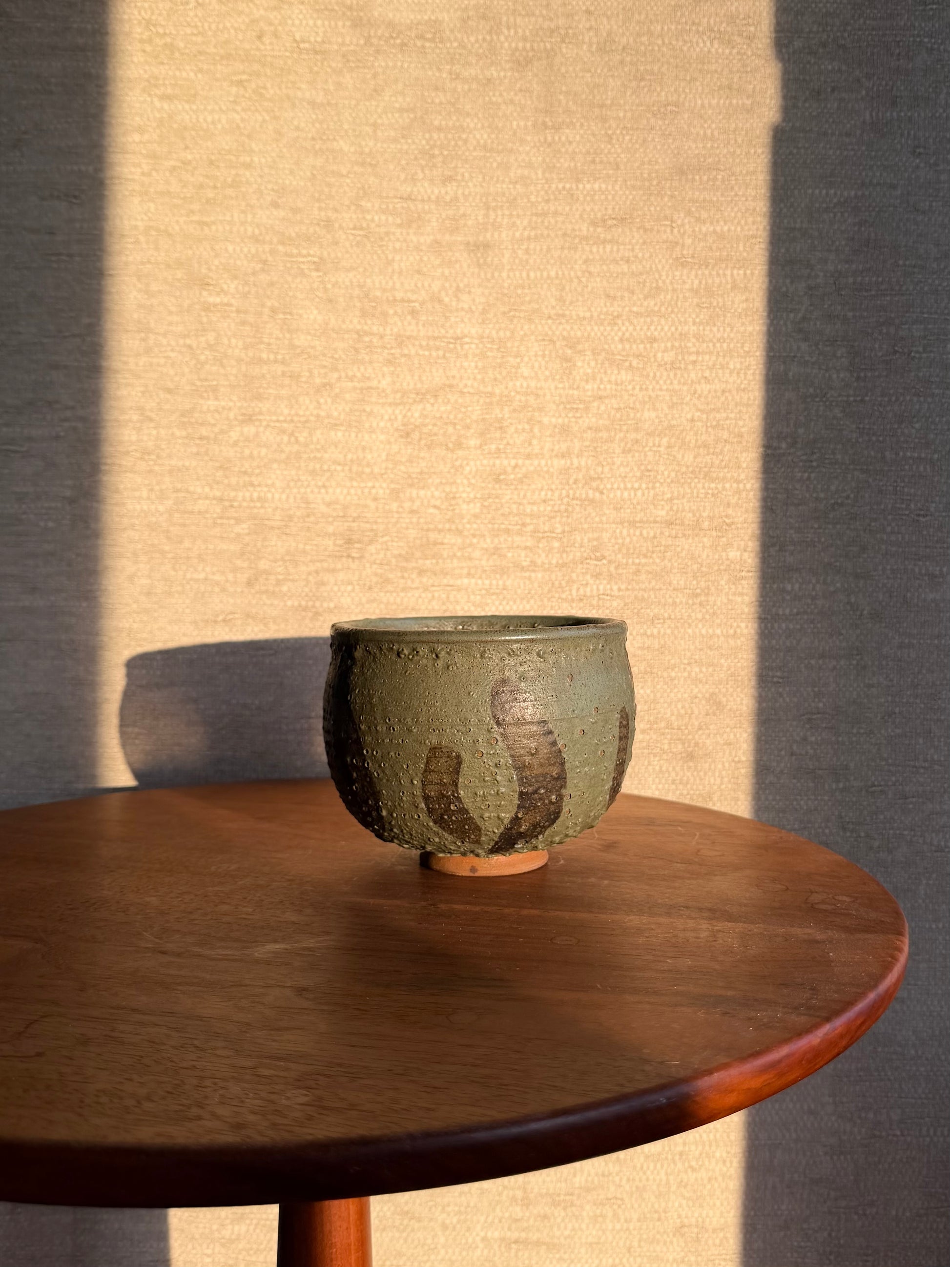 Ceramic bowl on a wooden table with a textured wall background