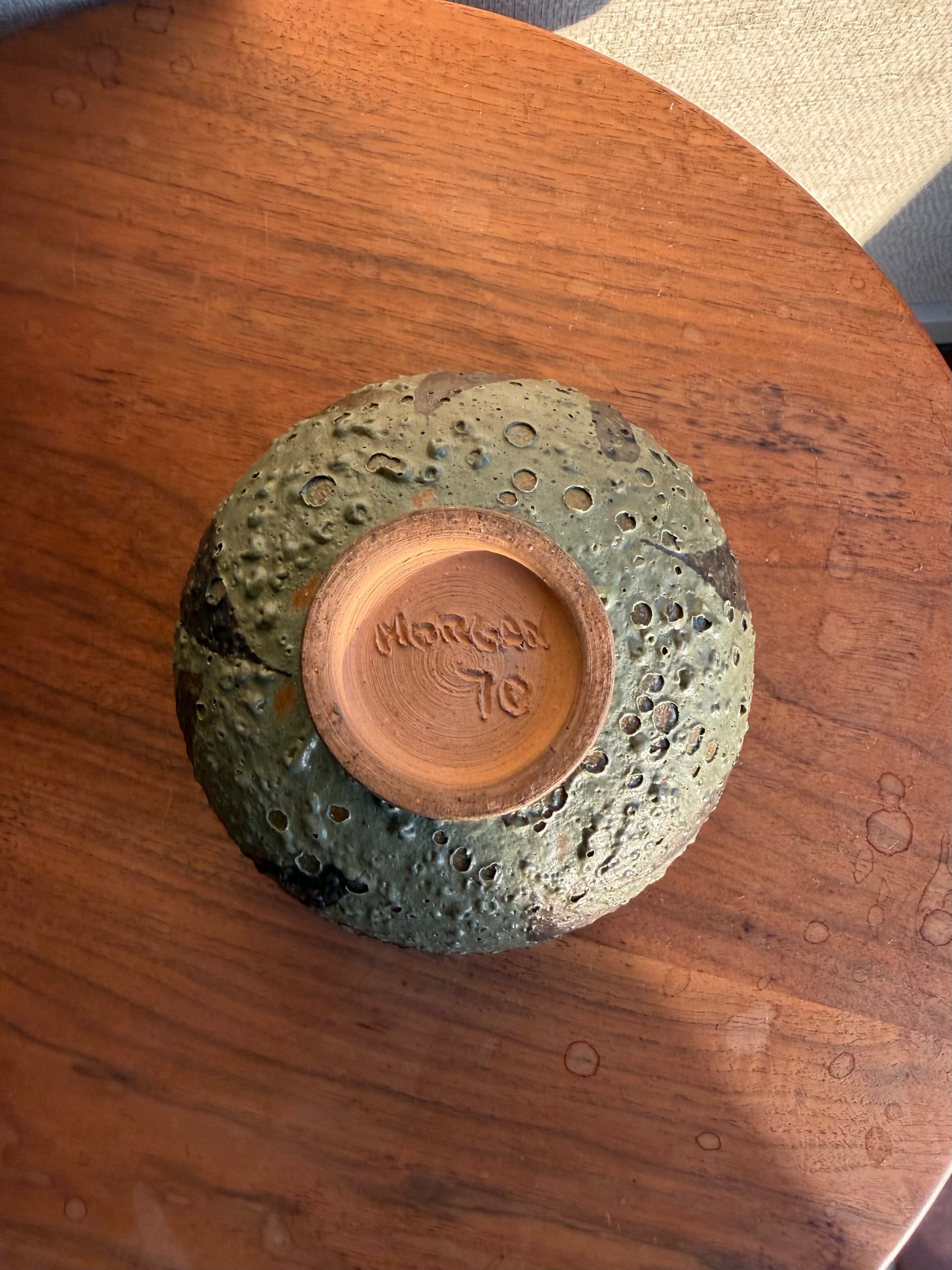 Ceramic bowl with textured surface and 'Morgan' branding on a wooden surface