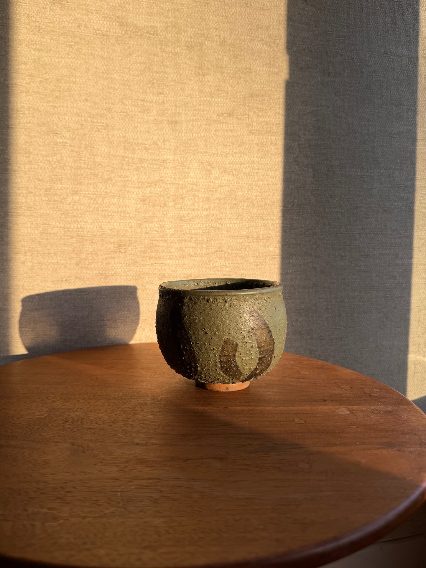 Green ceramic bowl on a wooden table with a textured wall background