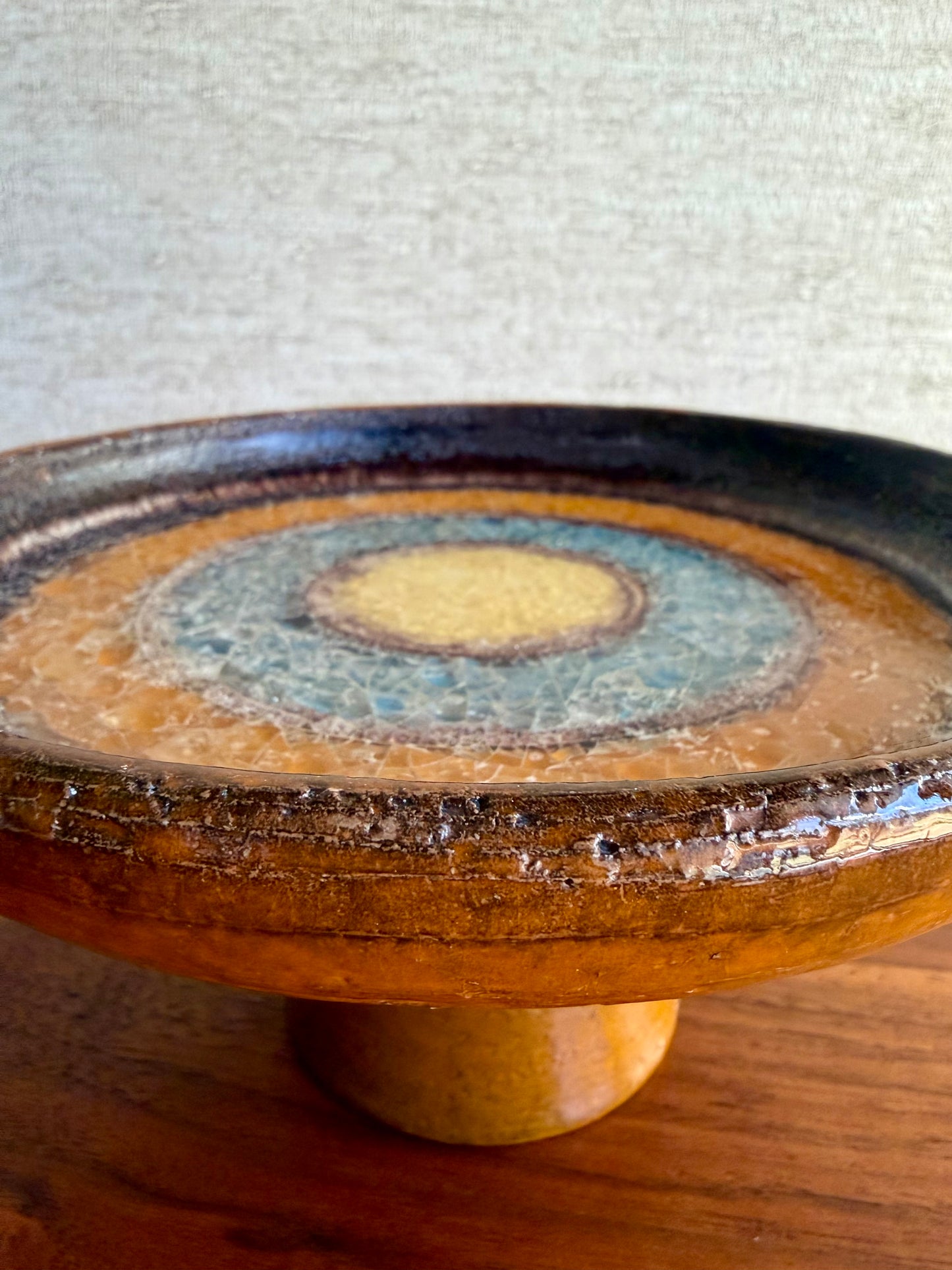Ceramic pedestal with decorative glaze pattern on a textured surface