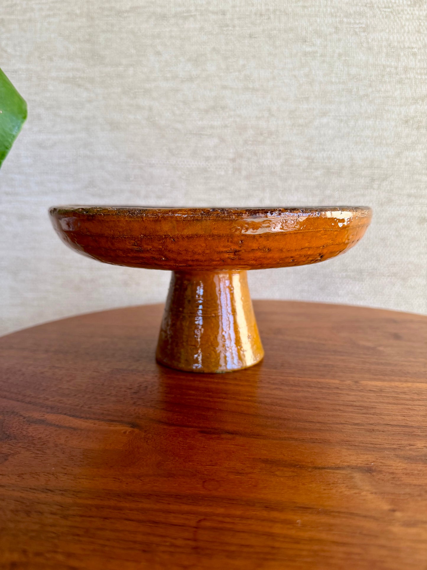 Wooden pedestal dish on a wooden surface with a neutral background