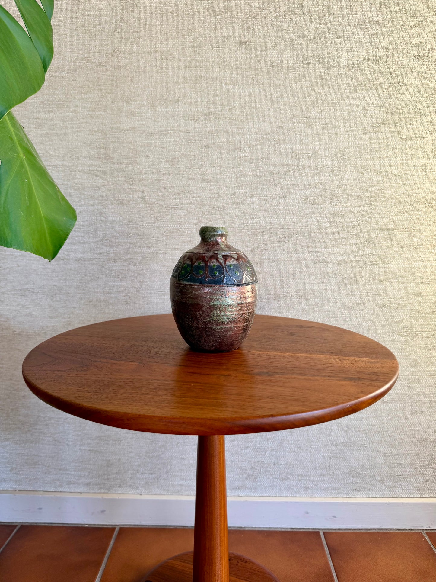 Wooden table with a ceramic vase on a textured wall background