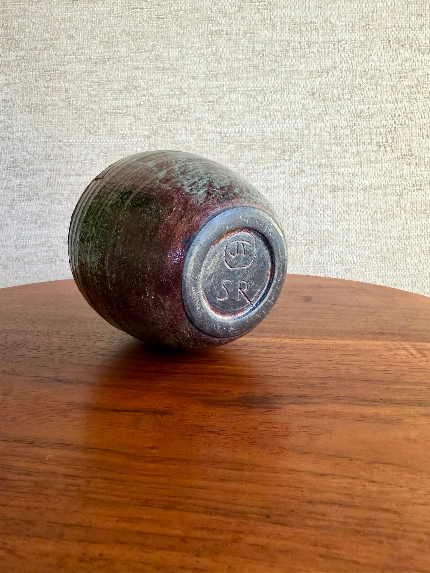 bottom of Vintage ceramic vase with a logo on a wooden table