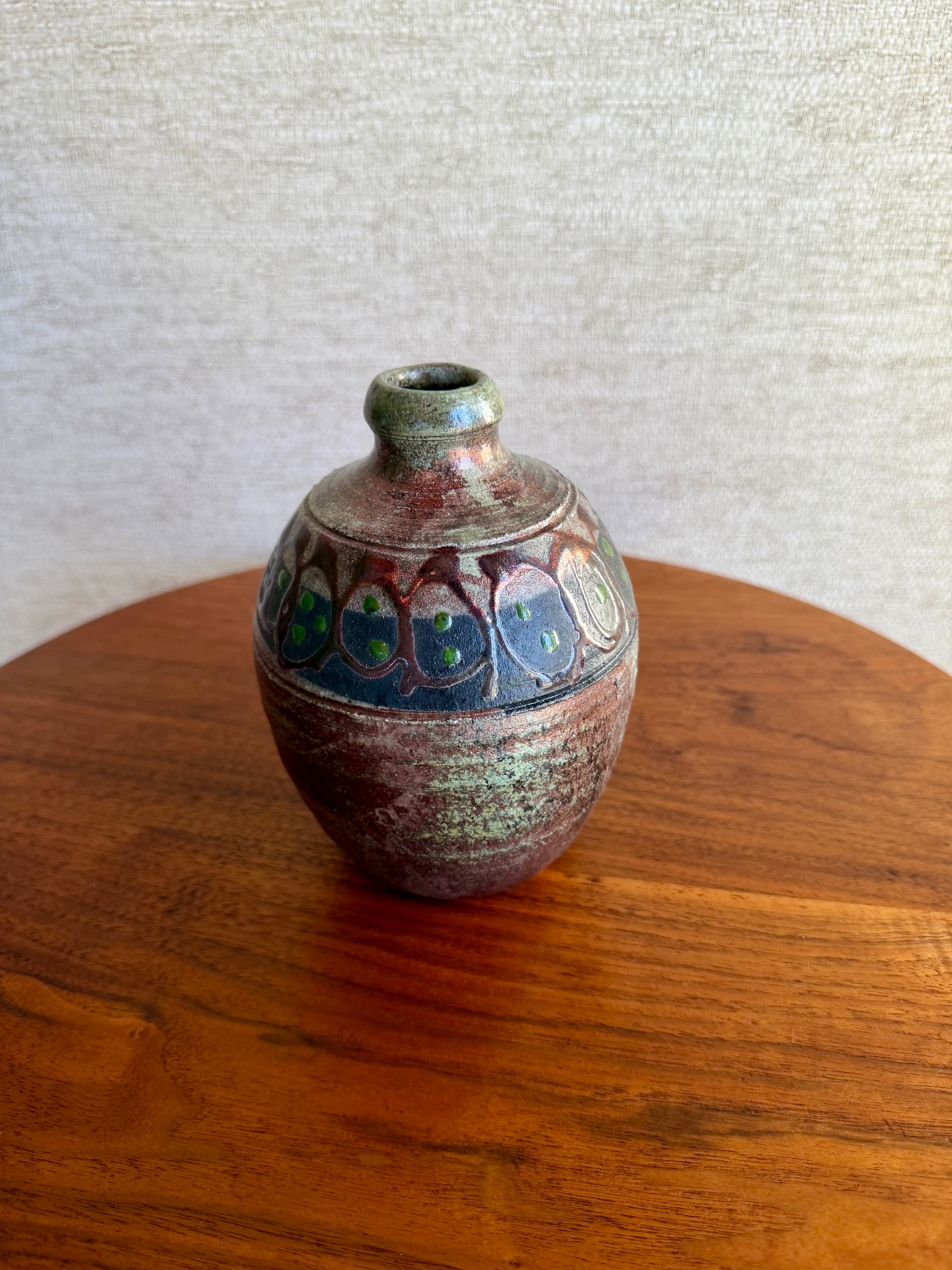 Small ceramic vase with decorative patterns on a wooden surface