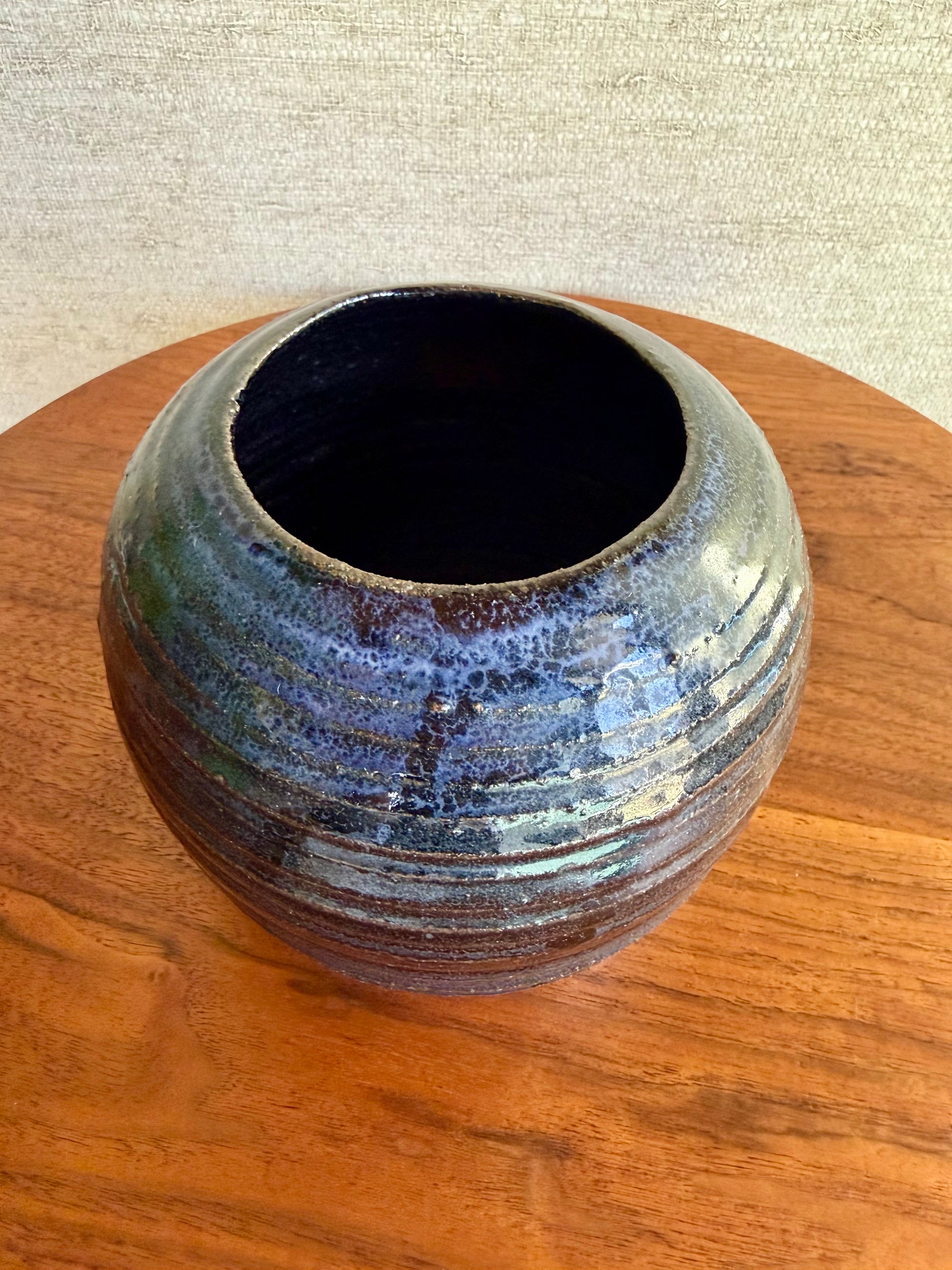 Ceramic vase with blue and brown glaze on a wooden surface