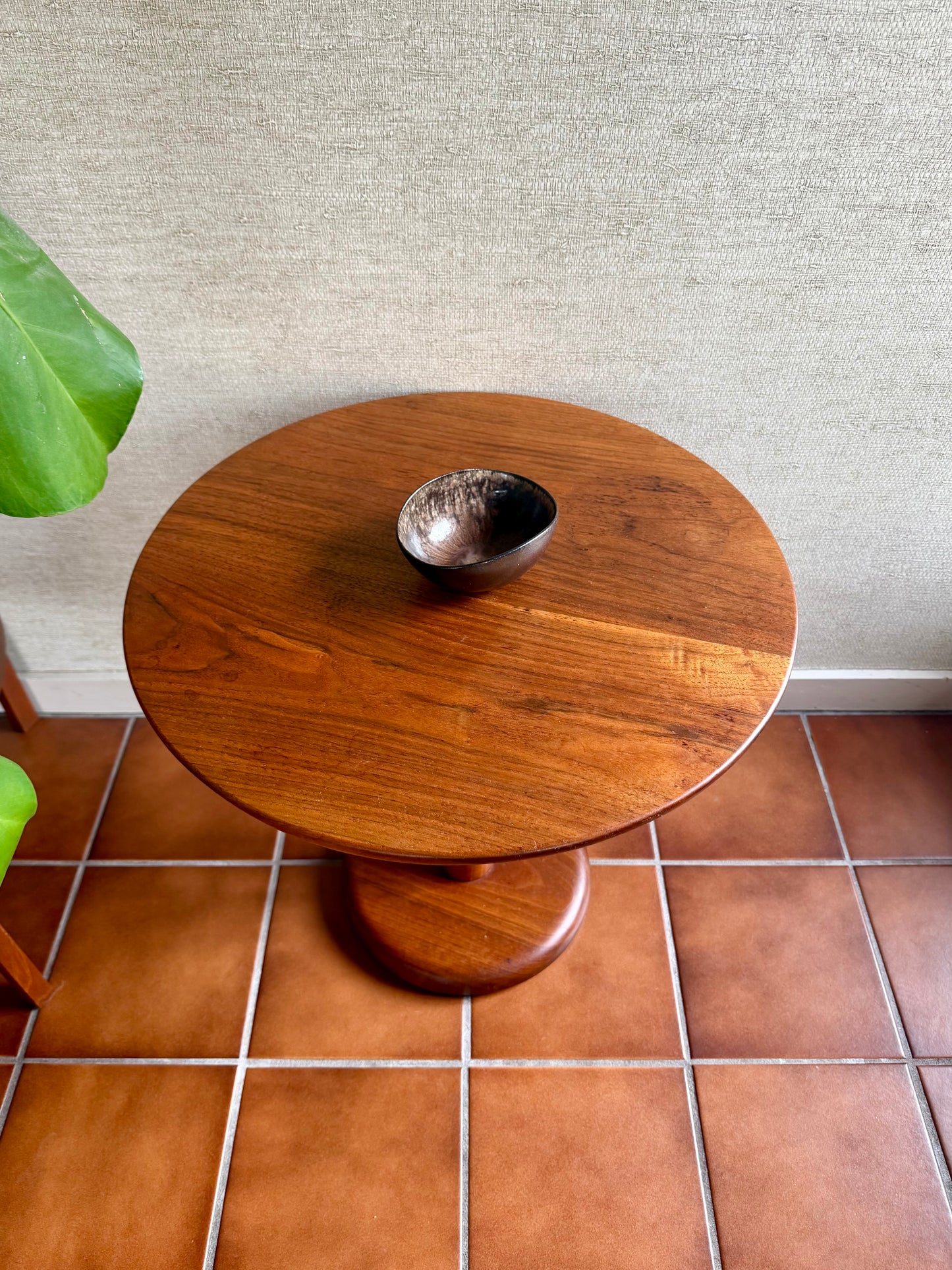 Wooden side table with a metallic bowl on a tiled floor