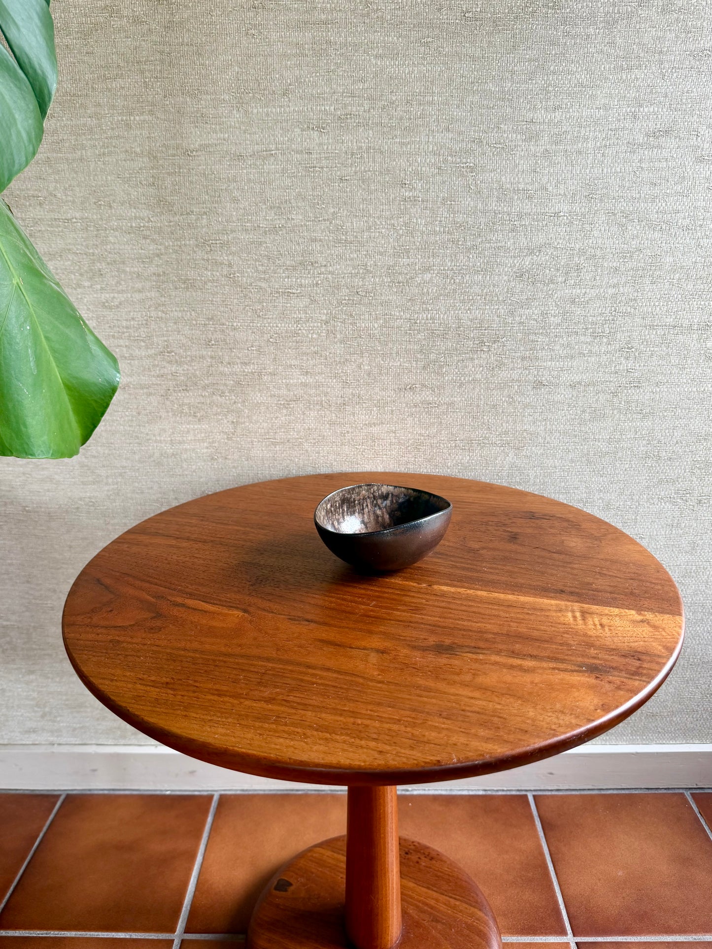 Wooden side table with a decorative bowl on a textured wall background