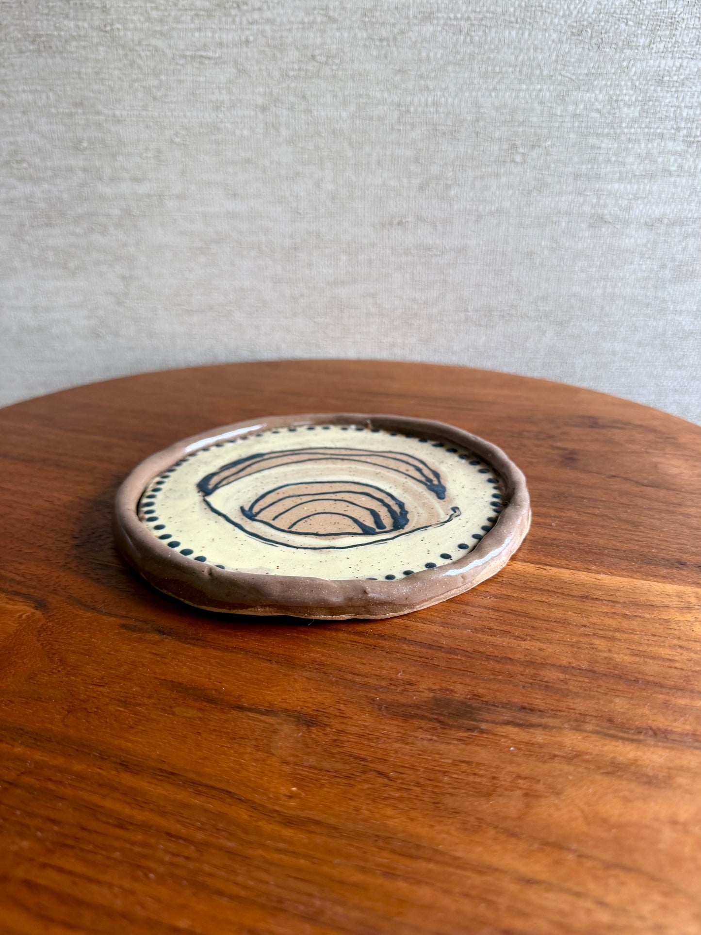 Ceramic coaster with decorative design on a wooden surface