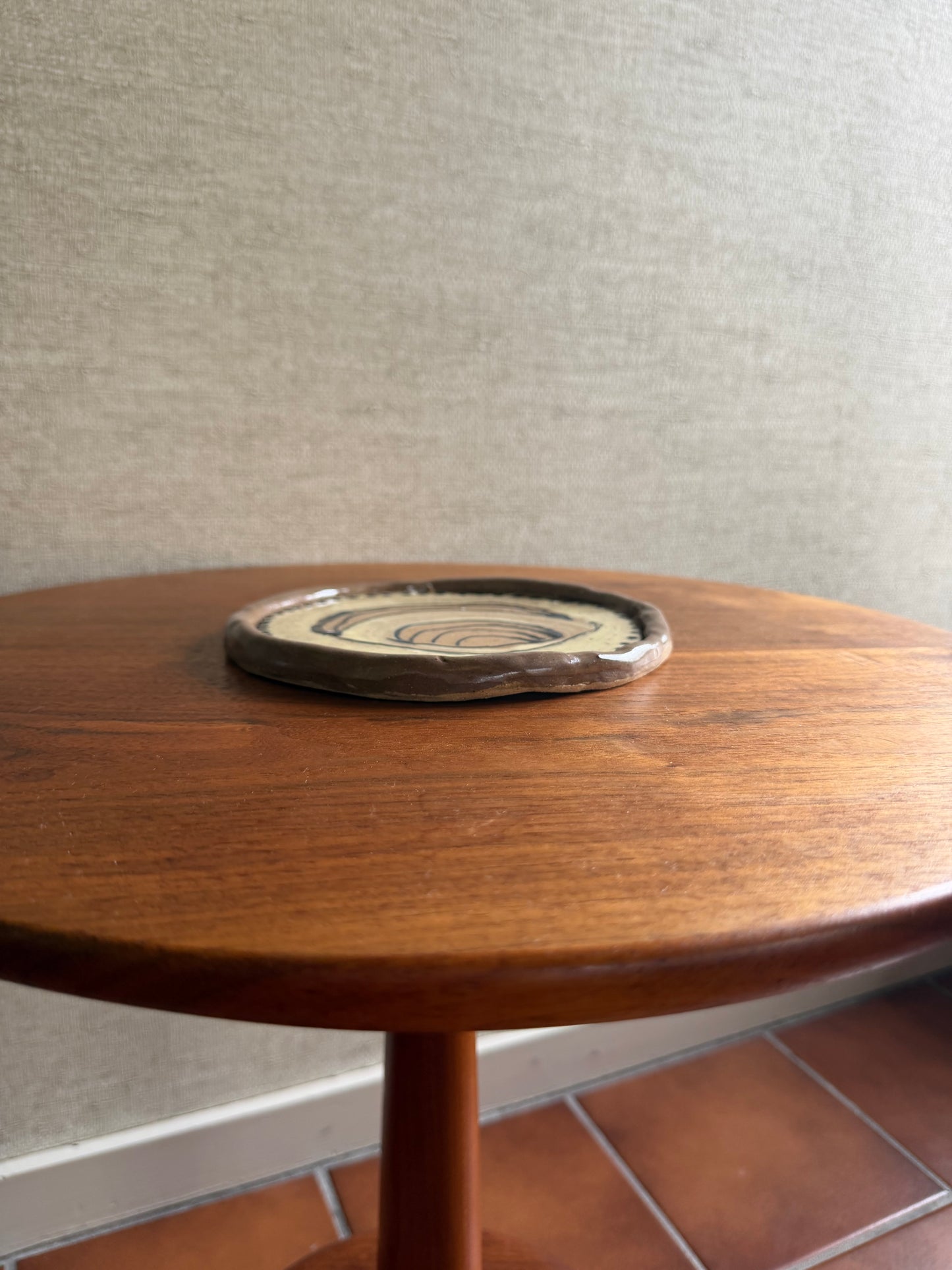 Close-up of a wooden wheel with a circular emblem on a textured surface.