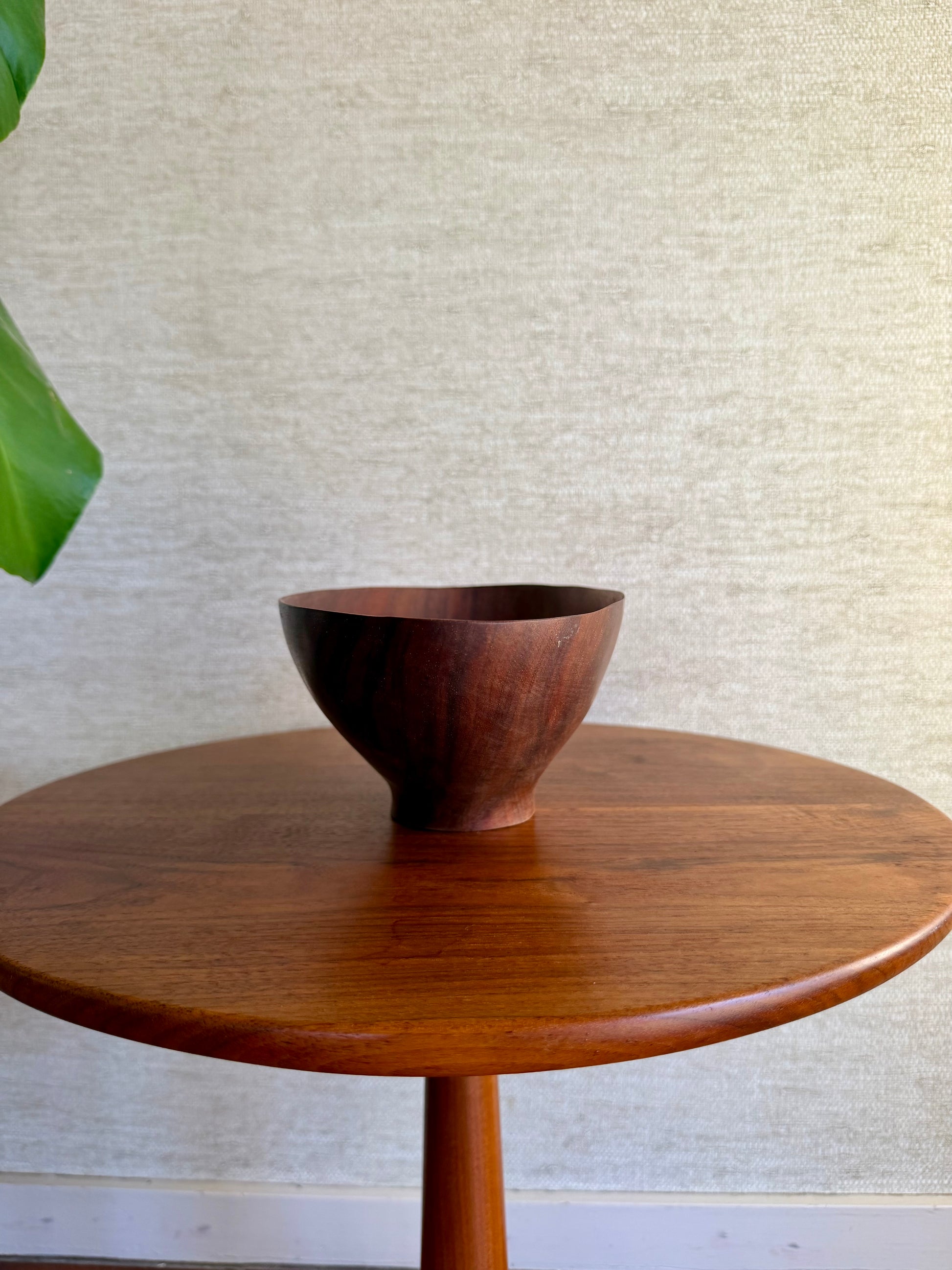 Wooden bowl on a round wooden table with a textured wall background