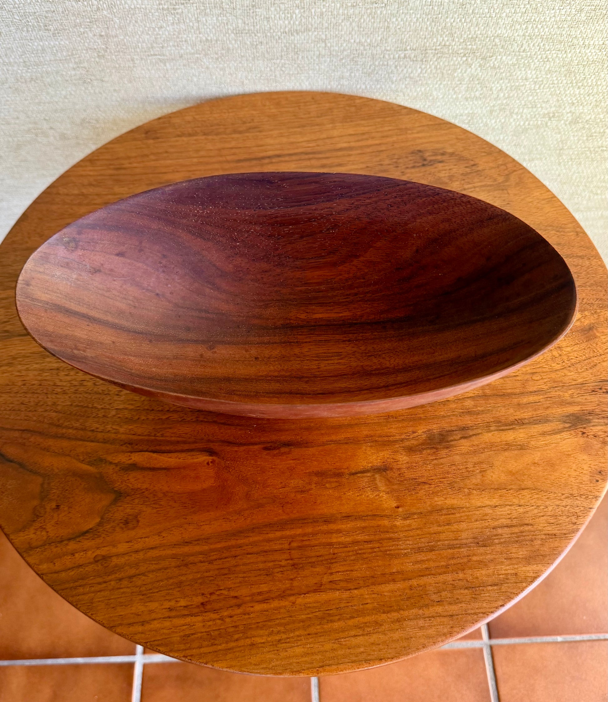 Wooden bowl with a rich, dark brown finish on a tiled floor.