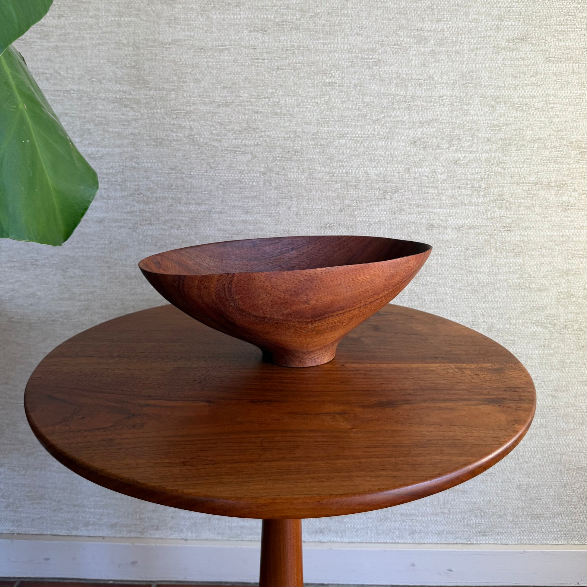 Wooden bowl on a wooden table against a textured wall.