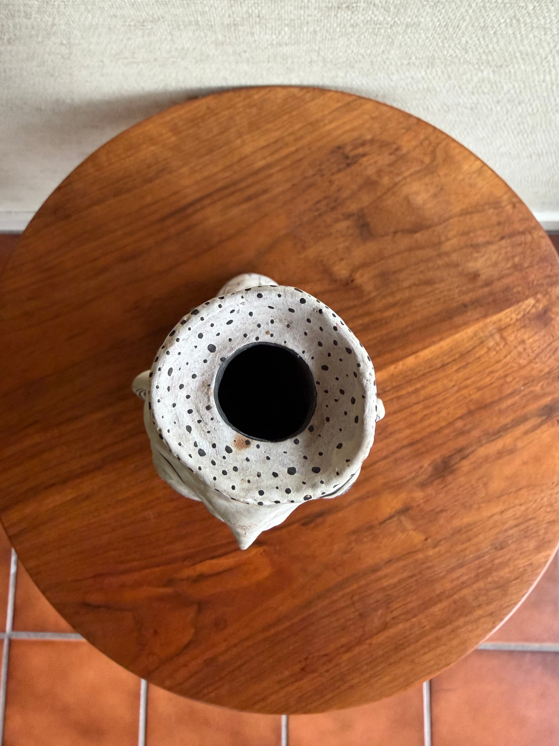 White ceramic vase with black speckles on a wooden surface