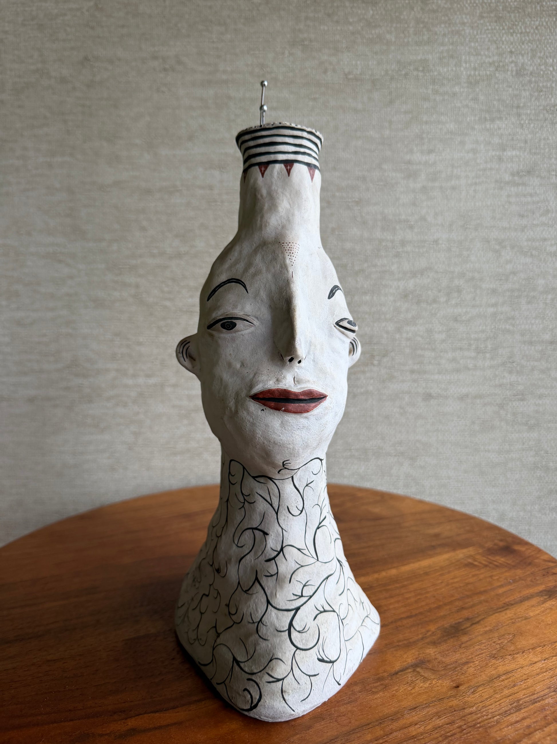 Ceramic sculpture of a face with intricate designs on a wooden surface