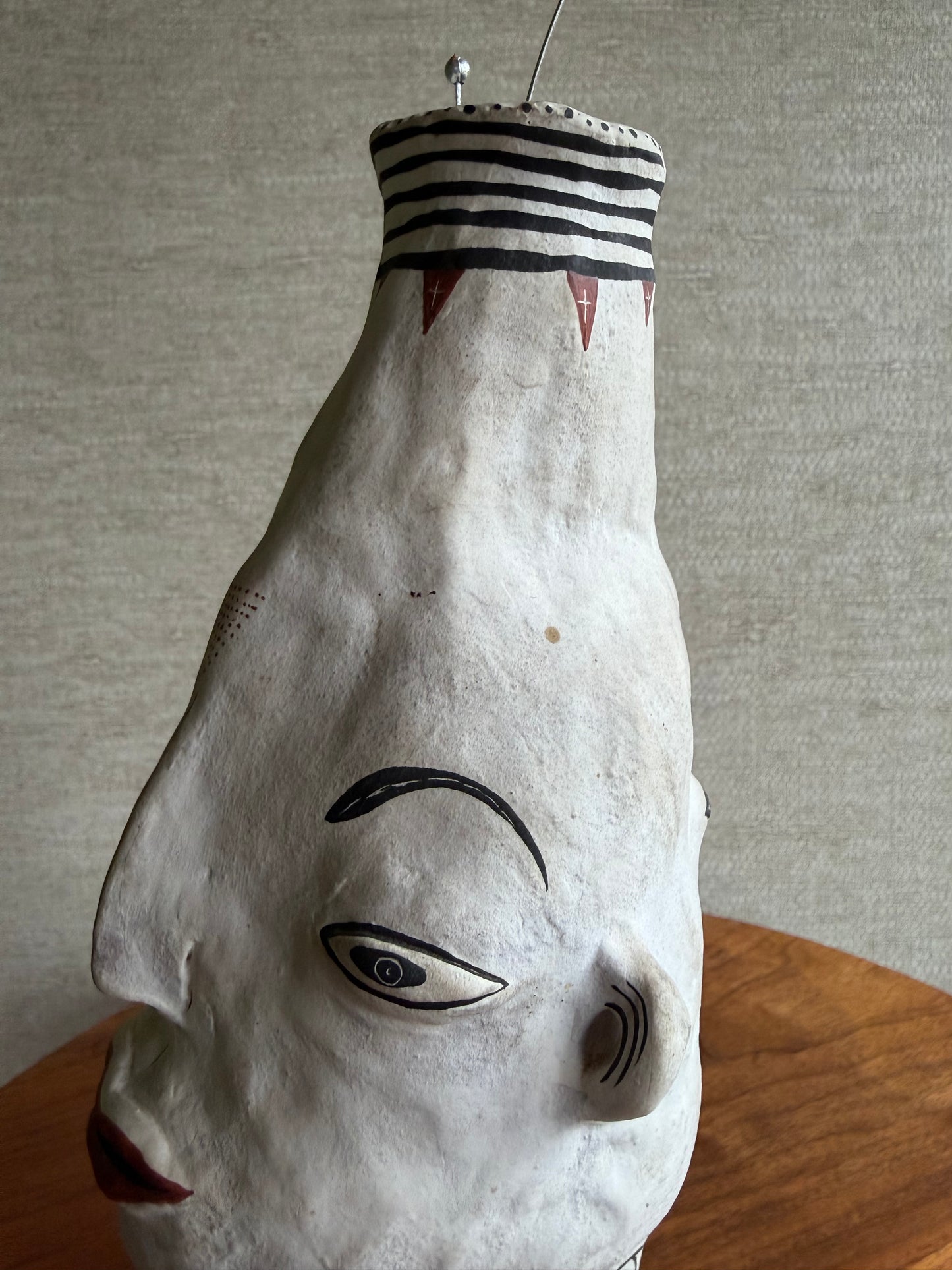 White face vase with black and red details on a neutral background