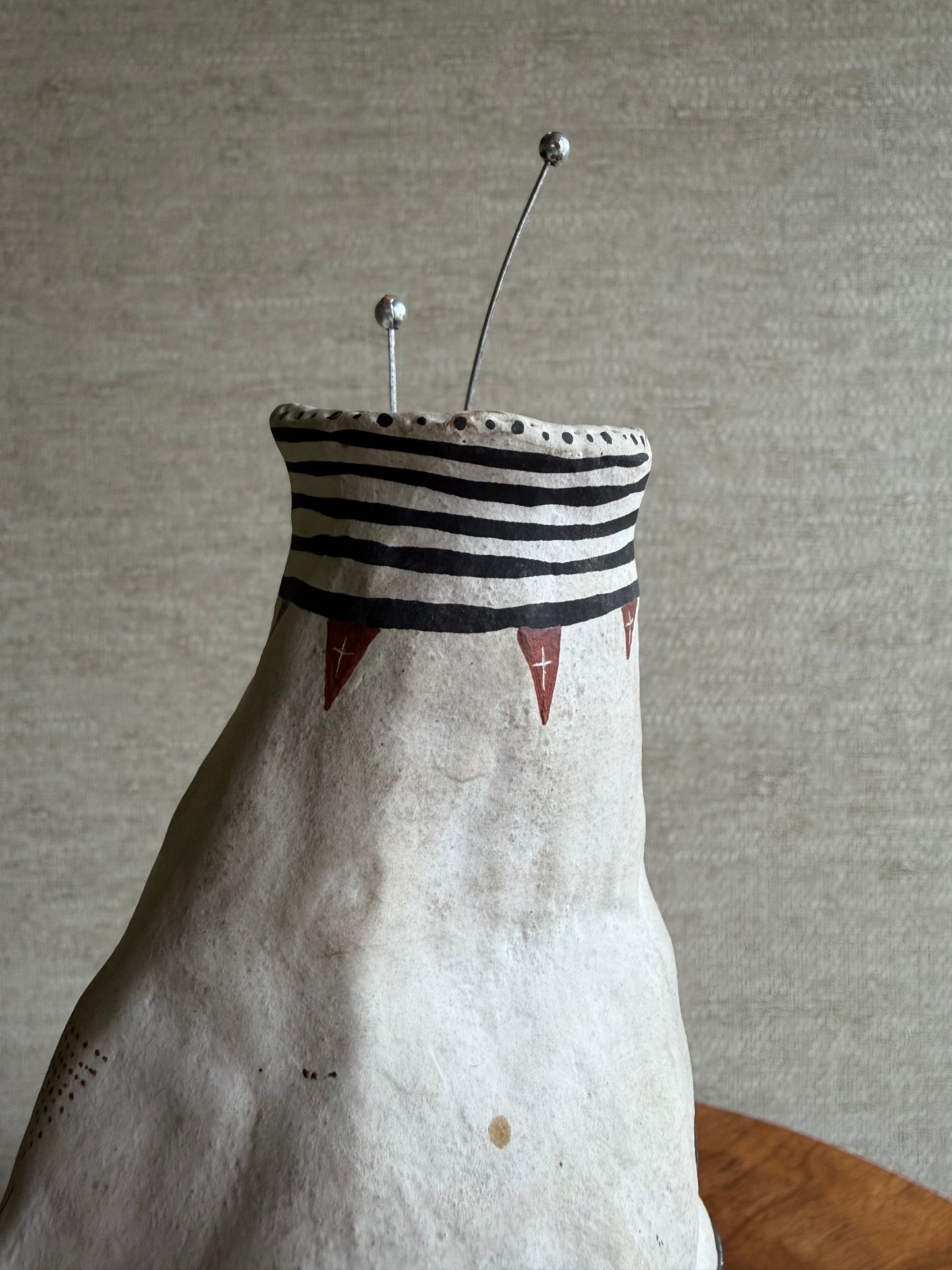 Decorative face vase with striped pattern on a neutral background
